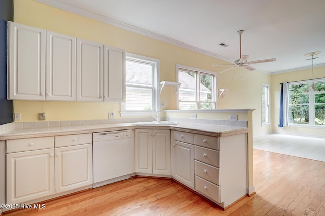 8500 Hammock Dunes Dr, Wilmington, NC 28411 - kitchen with white dishwasher, a peninsula, a sink, light wood-style flooring, and ornamental molding