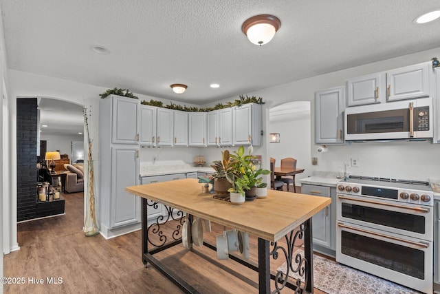140 One Down St, Southern Pines, NC 28387 - kitchen featuring stainless steel microwave, range with two ovens, arched walkways, light countertops, and a textured ceiling