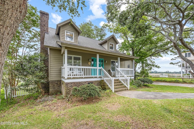 1137 Indigo Cir, Sunset Beach, NC 28468 - bungalow-style house featuring covered porch, a chimney, and roof with shingles