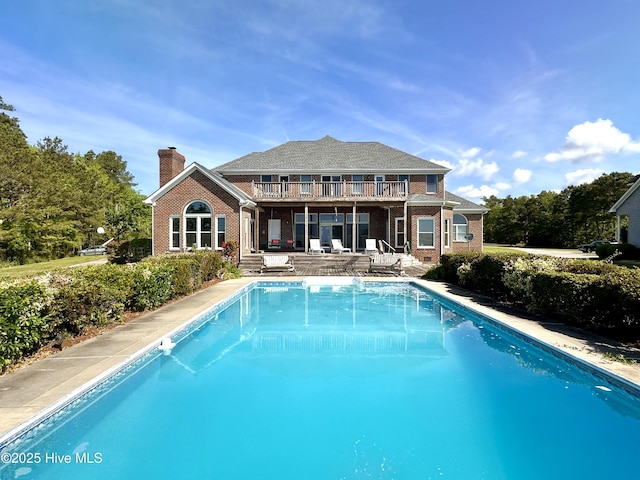 141 Baybreeze Dr, Shiloh, NC 27974 - back of house featuring brick siding, a balcony, a chimney, an outdoor pool, and a patio area
