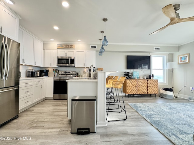 702 Carolina Beach Ave N Unit 3A, Carolina Beach, NC 28428 - kitchen featuring appliances with stainless steel finishes, ornamental molding, a kitchen breakfast bar, light wood-style flooring, and white cabinets