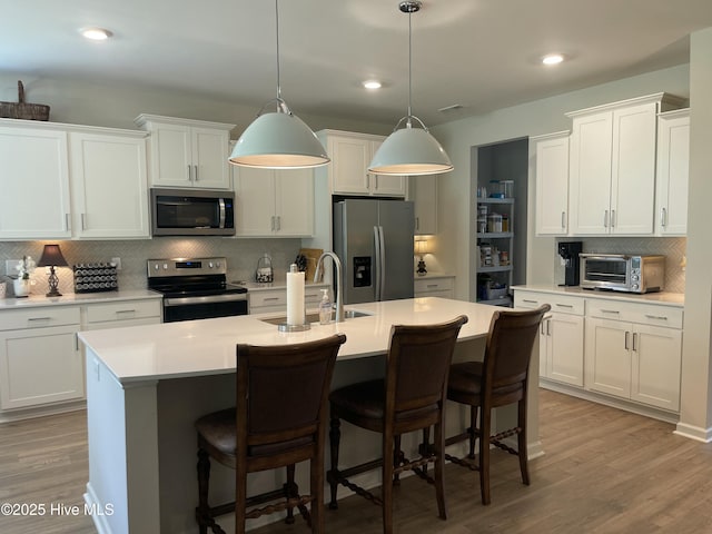 213 Woodsrun St, Raeford, NC 28376 - kitchen featuring stainless steel appliances, a sink, backsplash, a center island with sink, and light wood-style floors