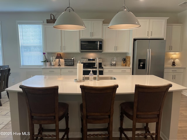 213 Woodsrun St, Raeford, NC 28376 - kitchen featuring appliances with stainless steel finishes, backsplash, light countertops, a kitchen island with sink, and hanging light fixtures