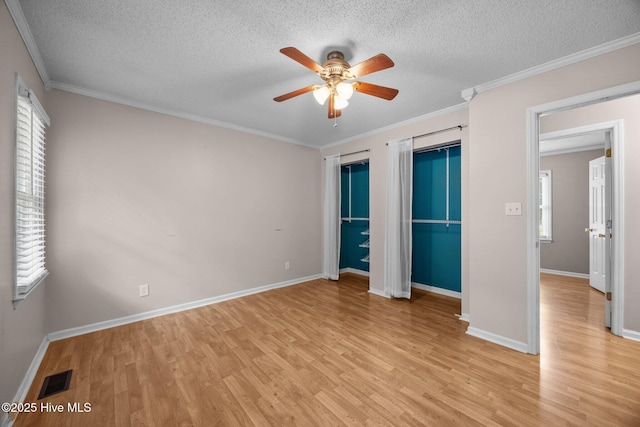 114 Maid Marian Ln, Washington, NC 27889 - unfurnished bedroom with light wood-style flooring, a textured ceiling, two closets, crown molding, and a ceiling fan
