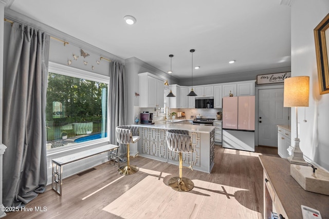 2221 Greaves Ct, Winterville, NC 28590 - kitchen with freestanding refrigerator, a peninsula, ornamental molding, wood finished floors, and white cabinetry