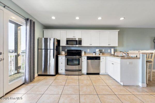 1505 N New River Dr Unit 210, Surf City, NC 28445 - kitchen with appliances with stainless steel finishes, healthy amount of natural light, a peninsula, white cabinets, and recessed lighting