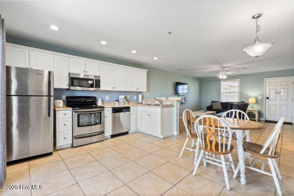1505 N New River Dr Unit 210, Surf City, NC 28445 - kitchen with stainless steel appliances, a peninsula, white cabinets, light tile patterned floors, and recessed lighting