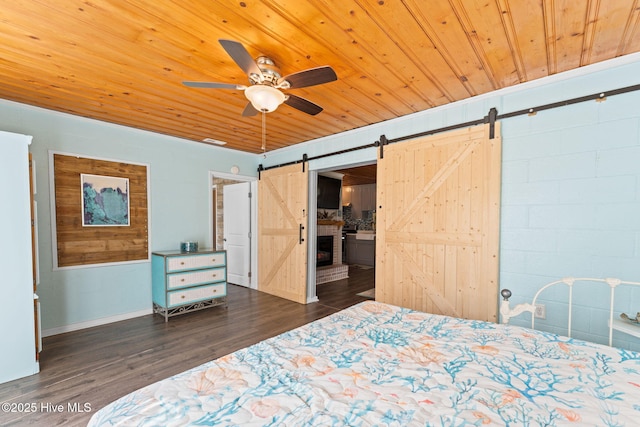 115 NE 66th St, Oak Island, NC 28465 - bedroom with a barn door, wood ceiling, dark wood-style floors, a ceiling fan, and baseboards