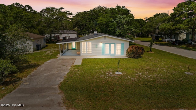 115 NE 66th St, Oak Island, NC 28465 - view of front facade featuring french doors, asphalt driveway, and a front lawn