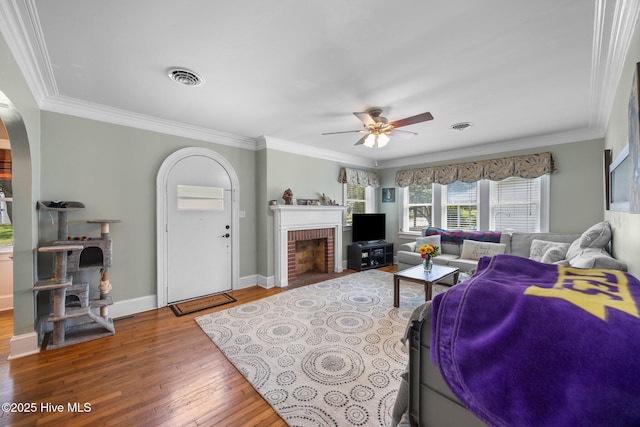 1208 N Bonner St, Washington, NC 27889 - living area with hardwood / wood-style flooring, a ceiling fan, a fireplace, arched walkways, and ornamental molding