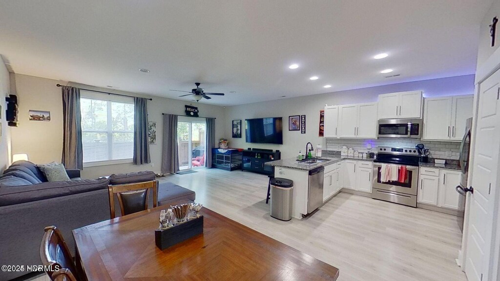11 Acacia Rd, Hampstead, NC 28443 - kitchen with stainless steel appliances, open floor plan, a peninsula, a sink, and light wood-type flooring