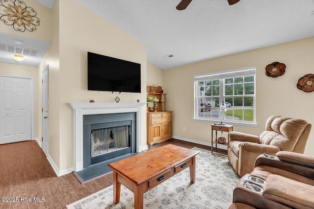 136 Van Riggs Rd, Hubert, NC 28539 - living area featuring wood finished floors, a ceiling fan, a fireplace with raised hearth, vaulted ceiling, and a textured ceiling
