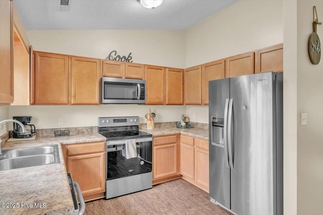 136 Van Riggs Rd, Hubert, NC 28539 - kitchen featuring appliances with stainless steel finishes, vaulted ceiling, light countertops, light wood-style flooring, and light brown cabinetry