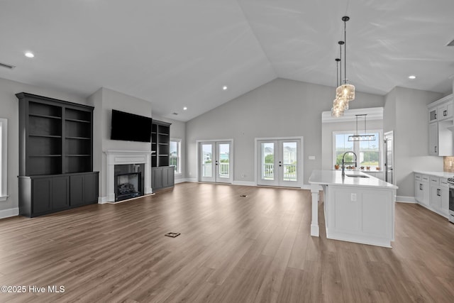 520 Cannonsgate Dr, Newport, NC 28570 - unfurnished living room featuring light wood-style floors, a fireplace, high vaulted ceiling, french doors, and a chandelier