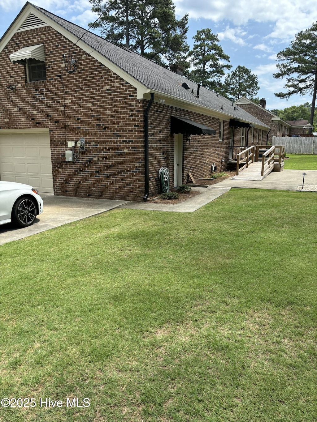 211 Forest Hills Rd NW, Wilson, NC 27896 - view of side of property featuring brick siding, an attached garage, and a shingled roof