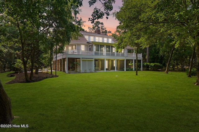 733 Legare Ln SW, Supply, NC 28462 - back of property at dusk with a sunroom, a yard, and a chimney