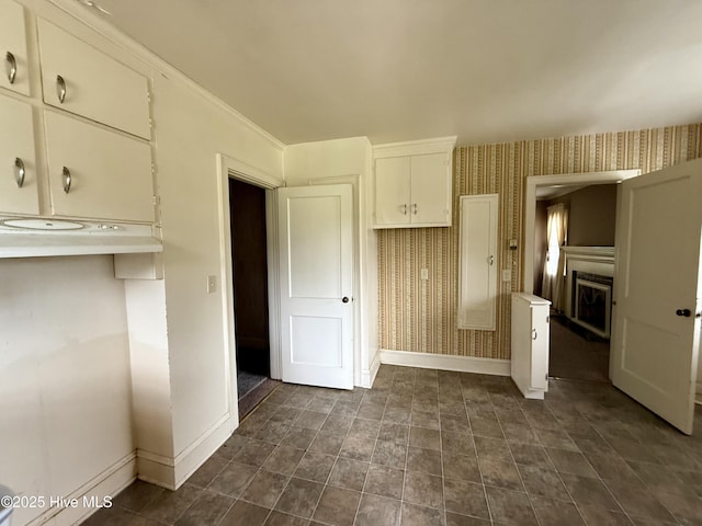 110 N Main St, Colerain, NC 27924 - kitchen featuring wallpapered walls, baseboards, a fireplace, and white cabinets