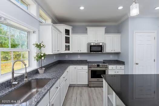 225 Factory Rd, Hampstead, NC 28443 - kitchen with stainless steel appliances, a sink, white cabinets, light wood-type flooring, and crown molding