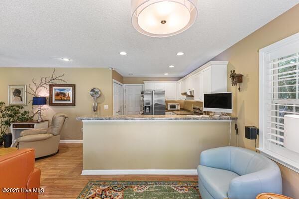 1135 Sunburst Way, Leland, NC 28451 - kitchen featuring stainless steel refrigerator with ice dispenser, open floor plan, light wood-style flooring, white microwave, and a peninsula