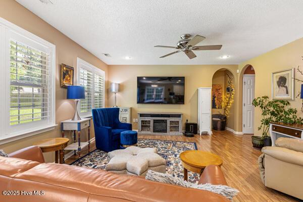1135 Sunburst Way, Leland, NC 28451 - living area featuring healthy amount of natural light, ceiling fan, wood finished floors, a textured ceiling, and arched walkways