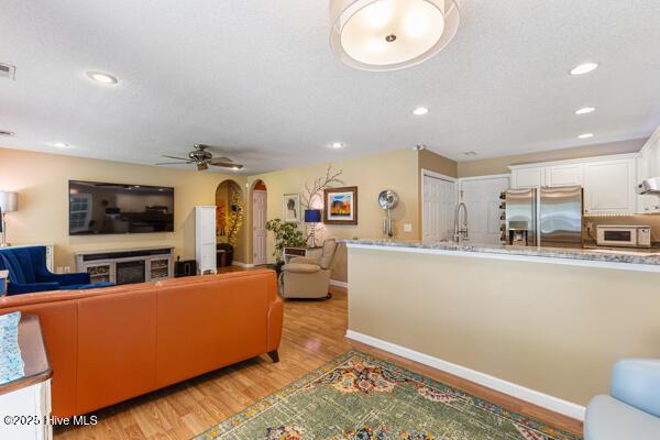 1135 Sunburst Way, Leland, NC 28451 - living room with arched walkways, light wood finished floors, ceiling fan, baseboards, and recessed lighting
