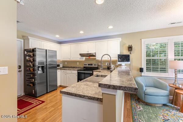 1135 Sunburst Way, Leland, NC 28451 - kitchen with stainless steel fridge with ice dispenser, range with electric stovetop, a sink, a peninsula, and light wood-style flooring