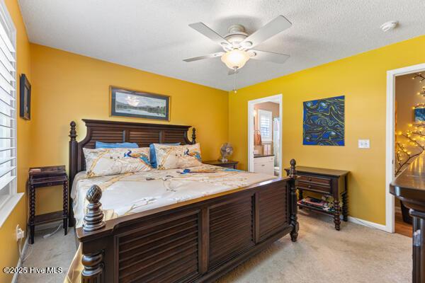 1135 Sunburst Way, Leland, NC 28451 - bedroom with light colored carpet, baseboards, ensuite bathroom, and ceiling fan