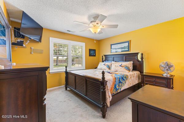 1135 Sunburst Way, Leland, NC 28451 - bedroom with light carpet, a textured ceiling, baseboards, and a ceiling fan