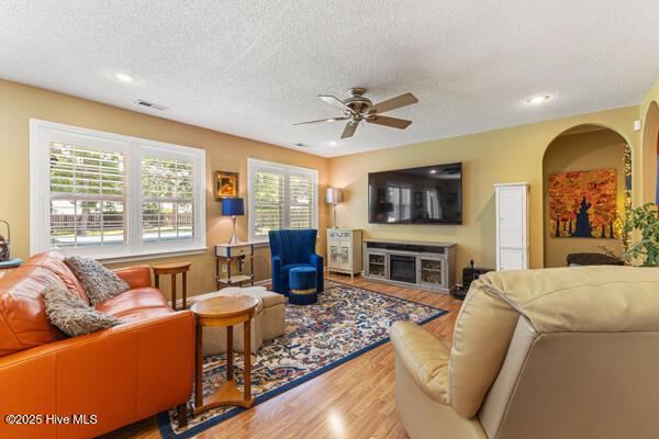 1135 Sunburst Way, Leland, NC 28451 - living area with wood finished floors, a ceiling fan, a textured ceiling, a fireplace, and recessed lighting