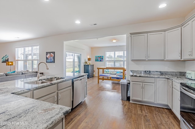 522 Heartwood Dr, Leland, NC 28479 - kitchen featuring stainless steel appliances, a sink, open floor plan, wood finished floors, and light stone counters