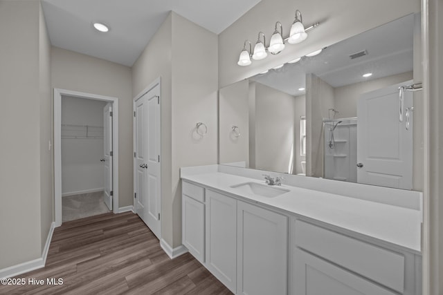 1008 Rodanthe Dr, New Bern, NC 28562 - bathroom featuring vanity, wood finished floors, a walk in shower, a spacious closet, and baseboards