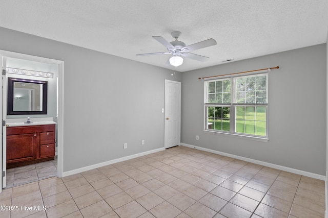 1001 Windgate Dr, Wilmington, NC 28412 - empty room with light tile patterned floors, ceiling fan, a textured ceiling, baseboards, and a sink