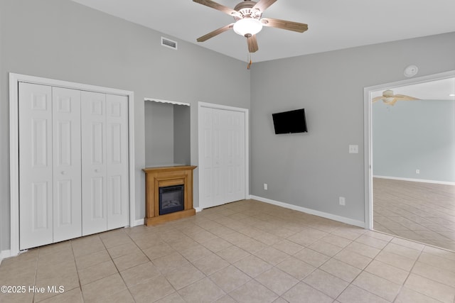1001 Windgate Dr, Wilmington, NC 28412 - unfurnished bedroom featuring two closets, light tile patterned floors, a glass covered fireplace, lofted ceiling, and baseboards