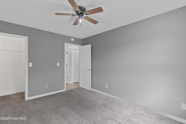 1001 Windgate Dr, Wilmington, NC 28412 - unfurnished bedroom featuring carpet floors, a walk in closet, baseboards, a closet, and a ceiling fan