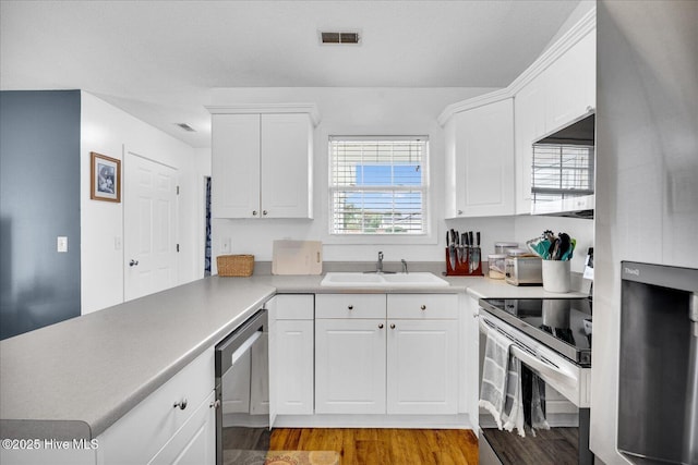 222 Bridgeton Ct, Wilmington, NC 28411 - kitchen with appliances with stainless steel finishes, wood finished floors, a sink, white cabinets, and light countertops