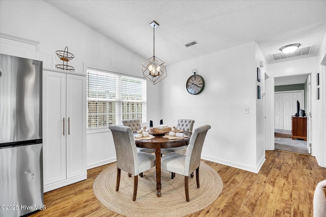 222 Bridgeton Ct, Wilmington, NC 28411 - dining space featuring light wood finished floors, baseboards, a textured ceiling, a chandelier, and lofted ceiling