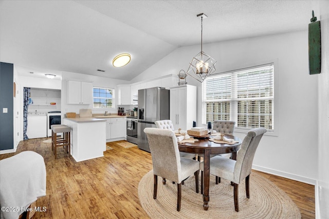 222 Bridgeton Ct, Wilmington, NC 28411 - dining space featuring light wood-style flooring, a chandelier, vaulted ceiling, washer / clothes dryer, and baseboards