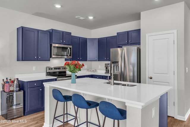 6751 Blacktip Ln, Wilmington, NC 28412 - kitchen with appliances with stainless steel finishes, blue cabinetry, light wood-style floors, a breakfast bar, and recessed lighting