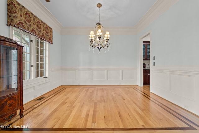 30 Spring Valley Ct, Pinehurst, NC 28374 - unfurnished dining area featuring a chandelier, light wood-style floors, ornamental molding, wainscoting, and a decorative wall