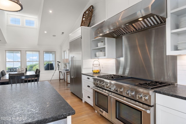 585 Forest Dunes Dr, Pine Knoll Shores, NC 28512 - kitchen featuring open shelves, high end appliances, wall chimney exhaust hood, dark countertops, and white cabinets