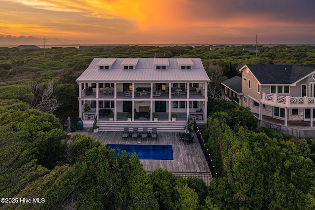 585 Forest Dunes Dr, Pine Knoll Shores, NC 28512 - rear view of house with a balcony, an outdoor pool, a metal roof, and a patio area