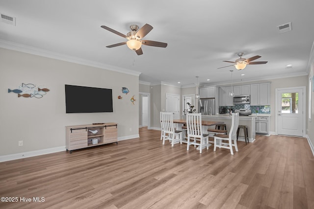 163 NE 31st St, Oak Island, NC 28465 - kitchen with stainless steel appliances, a ceiling fan, a kitchen bar, light wood-style floors, and an island with sink