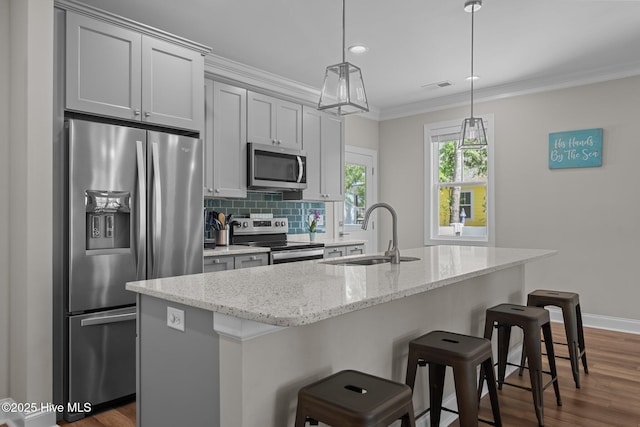 163 NE 31st St, Oak Island, NC 28465 - kitchen featuring stainless steel appliances, a sink, a breakfast bar, ornamental molding, and an island with sink