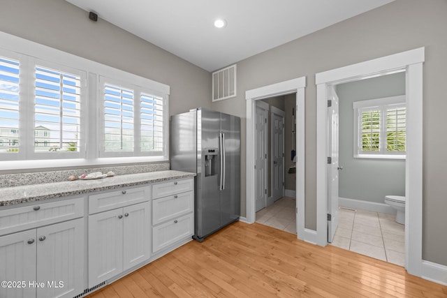 102 Seaside Ln, North Topsail Beach, NC 28460 - kitchen with stainless steel refrigerator with ice dispenser, white cabinetry, light wood finished floors, and light stone counters