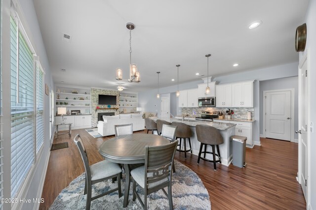 74 W Weatherbee Way, Hampstead, NC 28443 - dining room with recessed lighting, a stone fireplace, dark wood-style floors, a chandelier, and built in features