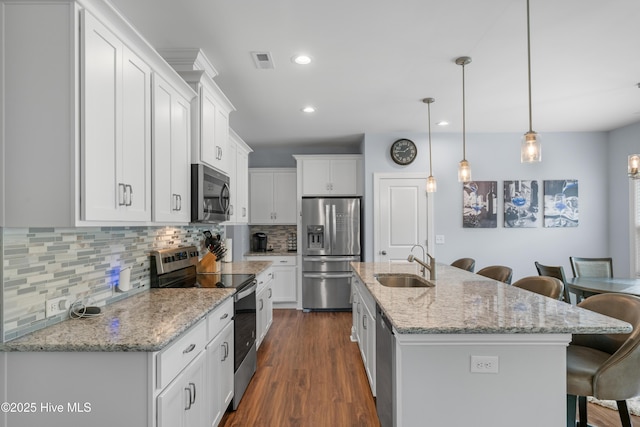 74 W Weatherbee Way, Hampstead, NC 28443 - kitchen with appliances with stainless steel finishes, a sink, a breakfast bar area, white cabinets, and tasteful backsplash