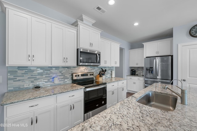 74 W Weatherbee Way, Hampstead, NC 28443 - kitchen with stainless steel appliances, a sink, white cabinets, decorative backsplash, and light stone countertops