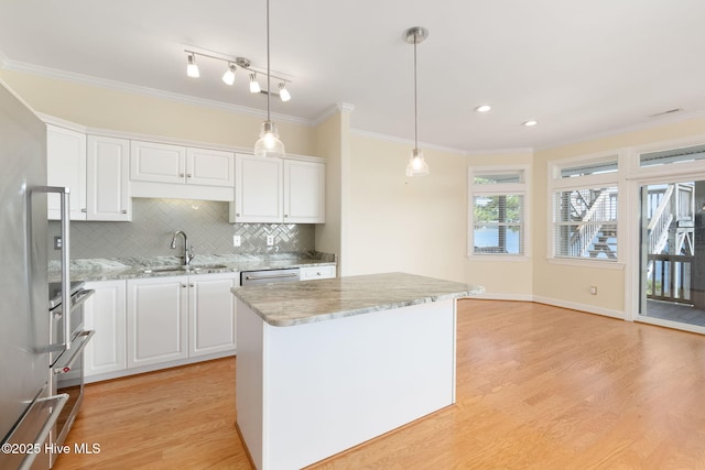 8630 Sound Dr Unit B2, Emerald Isle, NC 28594 - kitchen featuring ornamental molding, light wood-type flooring, white cabinets, backsplash, and light stone countertops