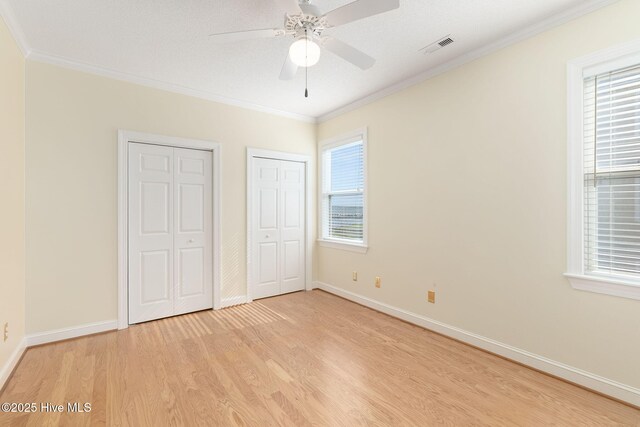 8630 Sound Dr Unit B2, Emerald Isle, NC 28594 - unfurnished bedroom featuring light wood-style flooring, two closets, ornamental molding, and ceiling fan