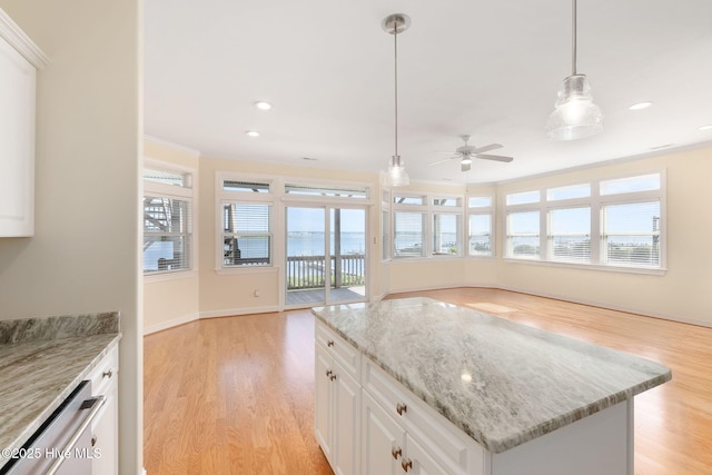 8630 Sound Dr Unit B2, Emerald Isle, NC 28594 - kitchen with light wood-type flooring, ceiling fan, hanging light fixtures, light stone countertops, and ornamental molding